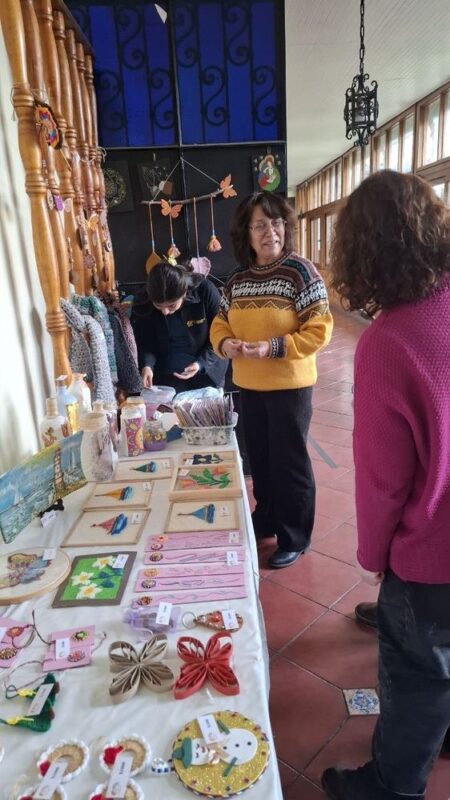 Mesa de manualidades de la Expo-Arcoa con visitas conversando
